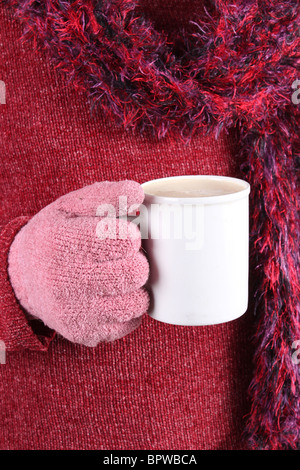 Person mit rosa Handschuhe, Schal und Pullover mit einem warmen Getränk in eine weiße Tasse an einem kalten Wintertag Stockfoto