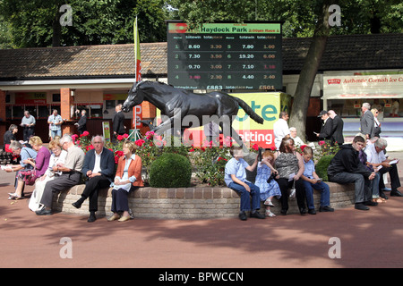 Menschen rund um die Gärten und Red Rum Statue am Betfred Sprint Cup Race Meeting sitzen, Haydock Park Racecourse Samstag, 4. September 2010 Stockfoto