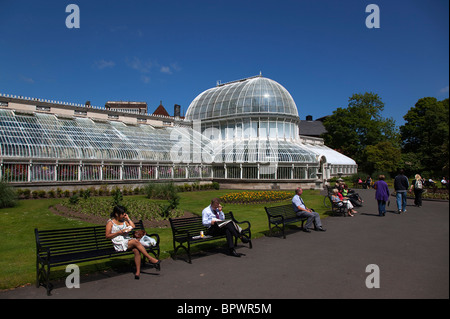 Irland, Nordirland, Belfast, botanische Gärten mit Menschen saßen auf den Bänken vor dem Palmenhaus neben Queens University. Stockfoto
