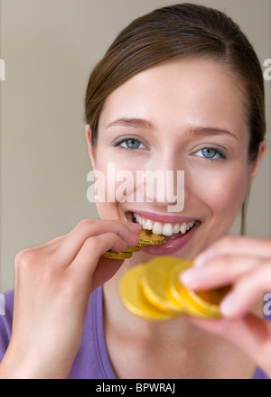 Frau beißt auf Goldmünzen Stockfoto