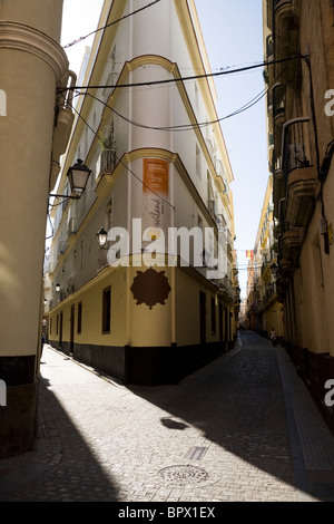 Typische traditionelle spanische gepflasterten Seitenstraße / Straße / Straße zusammen mit eckigen Gebäude und blauer Himmel. Cadiz, Spanien. Stockfoto