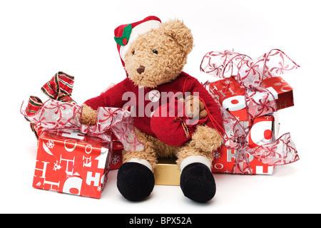 Teddy zu Weihnachten. Geliebten Kindes Teddy verkleidet als Weihnachtsmann sitzt unter verpackte Weihnachtsgeschenke. Stockfoto