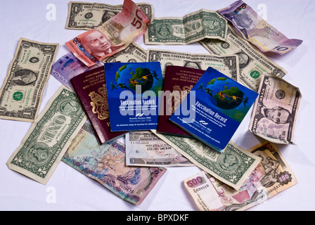 Vereinigtes Königreich-Pässe und Impfung Bücher Verlegung auf verschiedene Banknoten aus der ganzen Welt, einschließlich US-Dollar. Stockfoto