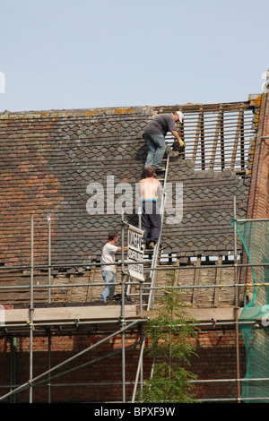 Bauherren, die Arbeiten auf dem Dach eines alten Gebäudes in Großbritannien. Stockfoto