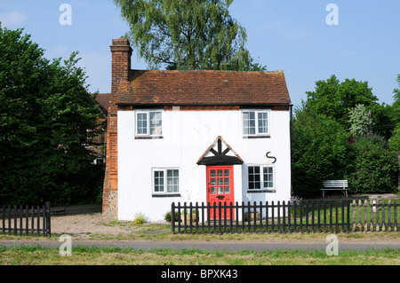 Ein weiß gefliesten englischen Landhaus mit roten Tür und Garten von vorne gesehen. Stockfoto