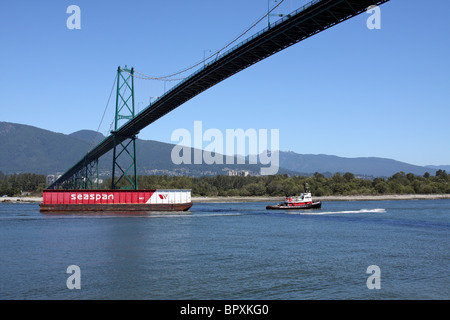 Ein Schlepper zieht ein Lastkahn unter Vancouvers Lions Gate Bridge Stockfoto