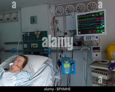 London England Private Intensivstation Seniorin im Krankenhausbett mit intravenösen Tropf und zeigt Herzfrequenz-Monitor Stockfoto