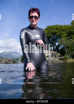 Eine Frau in Coniston Water etwa zur Teilnahme an der immer beliebter Aktivität im Freien oder Wild schwimmen. Stockfoto