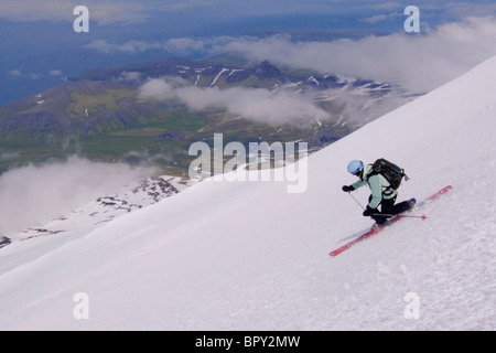 Eine Frau, Skifahren auf dem Gletscher über den Wolken am Mount Vsesevidov in den Aleuten in Alaska. Stockfoto