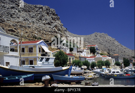 Boote und Häuser im Pedi, Symi Bucht. Dodekanes Griechenland. Stockfoto