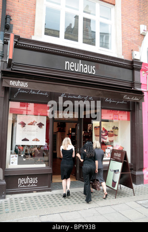 Drei junge Damen, die zu Fuß in den Newhaus Luxus belgische Chocolaterie in South Molton Street, London, UK. Stockfoto
