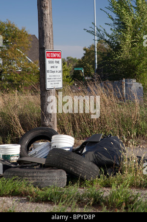 Detroit, Michigan - alte Reifen und anderen Müll wird in einer Gasse neben ein Schild Warnung vor Strafen für illegale Ablagerung abgekippt. Stockfoto