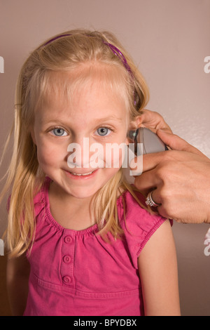 Kind mit einem Checkup in Arztpraxis, elektronische Thermometer im Ohr, wobei Temperatur Routineuntersuchung Stockfoto