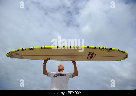 Ein Surfer, Ben Howey, hält ein Longboard Surfbrett am Strand von Fistral, Newquay, Großbritanniens Hauptstadt, in Cornwall Stockfoto