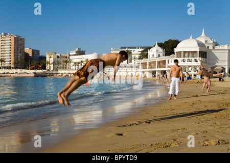 Spanische Teenager junge / Mann üben / übt seine Übung und akrobatischen Fähigkeiten auf einem sandigen Strand in Cadiz. Spanien. Stockfoto