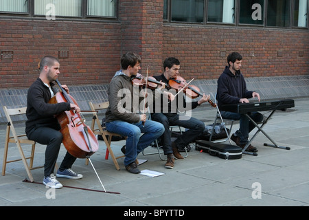 Vier Musiker als Straßenmusikant Geld, einem Sonntagabend in einer Straße in London in der Nähe von St. Pauls Cathedral Stockfoto