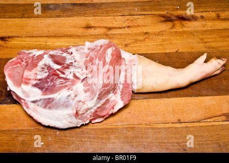 Halb gehäutet Schweinekeule ruht auf einem hölzernen Vorbereitungstisch Stockfoto