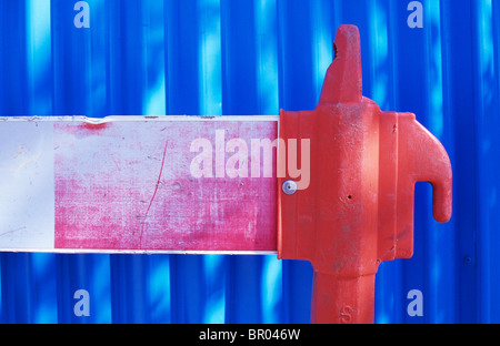 Detail des verblichenen temporäre Baustellen oder Werke Kunststoff Barriere mit blauen gewellten Wand oder Zaun hinter Gebäude Stockfoto