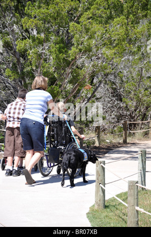Frau mit behinderten Kind im Rollstuhl und Diensthund besuchen Dinosaur World, Glen Rose, Texas, USA Stockfoto