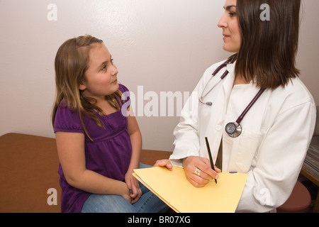 Ärztin Interviews achtjähriges Mädchen in einem pädiatrischen Kinderarzt-Büro bei der Prüfung der Tabelle Stockfoto