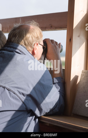 Vogelbeobachter aus in ein Versteck mit dem Fernglas betrachten. Stockfoto