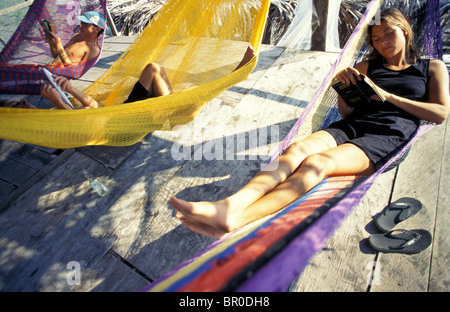 Eine Frau liest ein Buch in der Hängematte auf einem Deck. Stockfoto