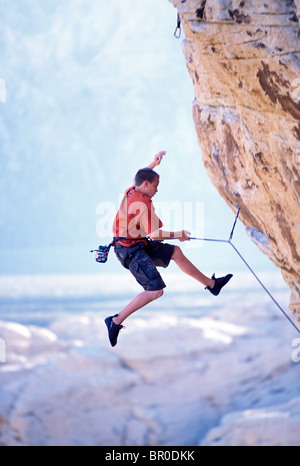 Ein junges Männchen rock Climber fallen / Klettern auf einem überhängenden Route in der Wüste. Stockfoto