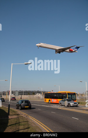 Ein SAS-Flugzeug landen am Flughafen Heathrow, London, Busse und Autos auf der Perimeter Road vorbei kommen. Stockfoto