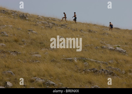Drei Personen klettern einen grasbewachsenen Hügel auf einer Inseln im Kornati-Nationalpark in der Adria. Stockfoto
