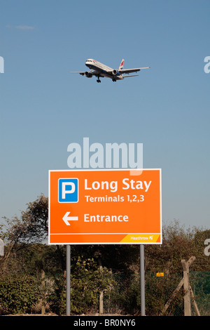 Ein Long Stay Parkplatz Schild mit British Airways Flugzeug kommen, um auf die nördlichen Start-und Landebahn am Flughafen Heathrow, London, UK landen. Stockfoto