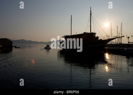 Ein Boot ist gegen eine geringe, Sommersonne im Hafen auf der Insel Iz in der Adria, Kroatien Silhouette. Stockfoto