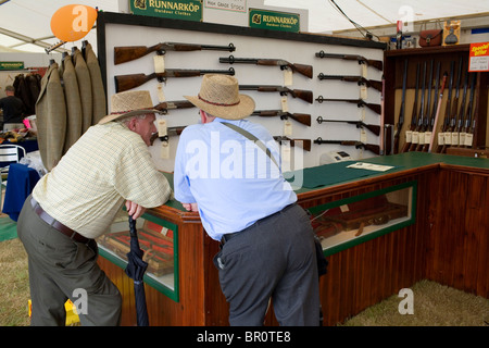 Zwei Männer in Hüten sprechen in einen Waffenladen. Stockfoto