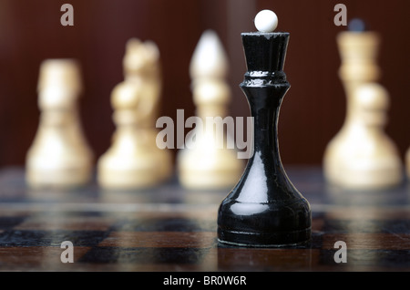 Schach-Spiel. Schwarze Dame gegen die Gruppe von weißen Schachfiguren. Close-up horizontale Foto Stockfoto