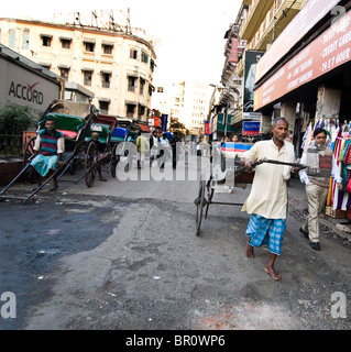 Ein Mann zieht eine Rikscha ist eine gemeinsame Szene in Kolkata, Indien. Stockfoto
