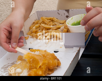 Nahaufnahme einer Person essen Fisch, Chips und Erbsenpüree in St Davids, Pembrokeshire Wales Stockfoto