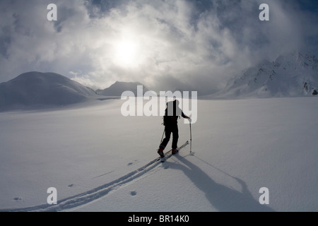 Backcountry Skifahrer kreuzt Gletscher unter Gewitterhimmel späten Tag. Stockfoto