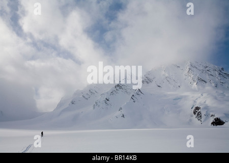 Backcountry Skifahrer kreuzt Gletscher unter Gewitterhimmel späten Tag. Stockfoto