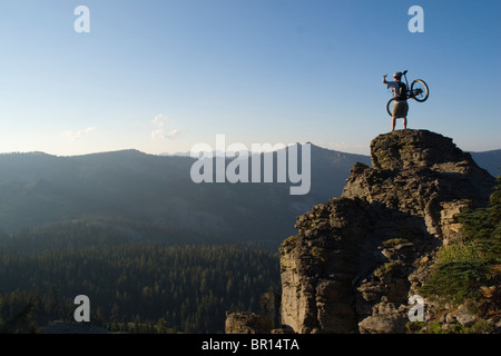 Ein Mountainbiker auf einem Turm bei Sonnenuntergang auf Barker Pass über dem Lake Tahoe in Kalifornien. Stockfoto