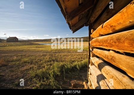 Die Seite des Log-Scheune mit Ranch-Haus im Hintergrund auf dem Uncompahgre Plateau, Colorado. Stockfoto