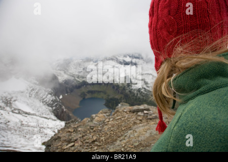 Ein Bergsteiger im Glacier National Park schaut auf verborgenen See als Sommer-Schnee-Sturm in den Bereich bewegt. Stockfoto