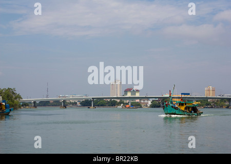 Angelboot/Fischerboot verlassen der Mündung des Flusses Kuantan mit der Stadt und die Brücke im Hintergrund Stockfoto