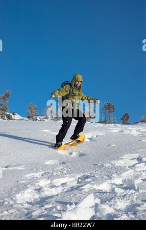 Eine junge Frau auf einem verschneiten Hügel in Schneeschuhen Stockfoto