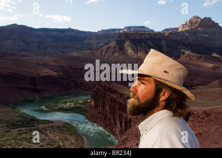 Ein Mann mittleren Alters in einem Cowboy-Hut blickt über den Colorado River im Grand Canyon National Par, Arizona. Stockfoto