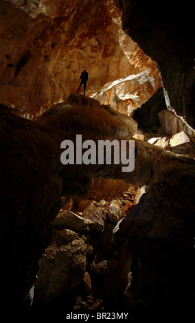 Ein einsamer Höhlenforscher steht am Anfang eine Steinbrücke in einem großen Felsbrocken übersäten Tunnel, tief im Inneren Whiterock (Höhle), in Mulu Nati Stockfoto