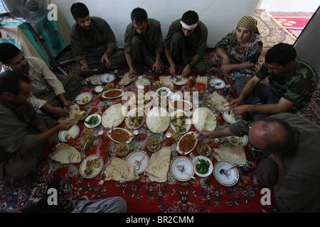 Eine Gruppe kurdischer Kämpfer der Volksverteidigungskräfte HPG, dem militärischen Flügel der Kurdischen Arbeiterpartei PKK, isst traditionelle kurdische Lebensmittel in einem sicheren Haus in einer ländlichen Siedlung in den Kandil-Bergen, einem Berggebiet nahe der irakischen Grenze zum Iran Stockfoto