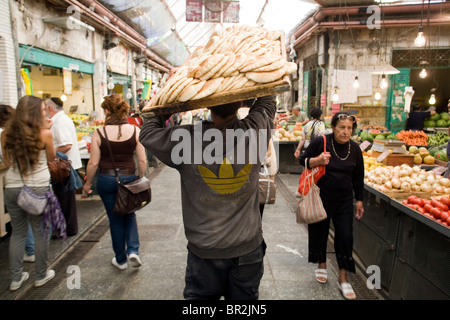 Ein Mann trägt Brot bei einem Versuch durch Mahane Yehuda Markt, Jerusalem, Israel Stockfoto