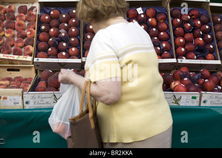 Eine Frau wählt Pfirsiche an einem Stand auf dem Markt auf Rue Mouffetard, einen berühmten Lebensmittelmarkt in Paris Stockfoto