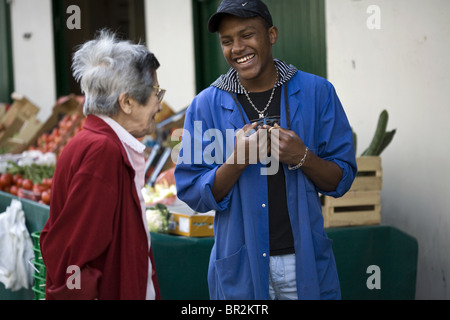 Eine Verkäuferin Witze mit einem älteren Kunden auf die Rue Mouffetard, einen berühmten Lebensmittelmarkt in Paris Stockfoto