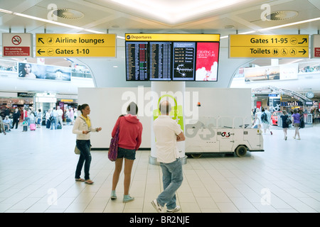 Passagiere, die Blick auf die Anzeigentafel, Abfahrten, Süd-Terminal, Flughafen Gatwick UK Stockfoto