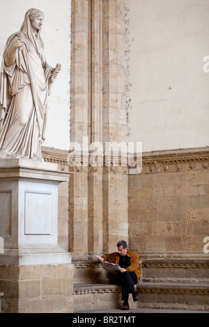 Sabine Frauen Statue aus der Zeit des Trajan - Hadrian wacht über Mann liest die Zeitung an der Loggia dei Lanzi in Florenz Stockfoto